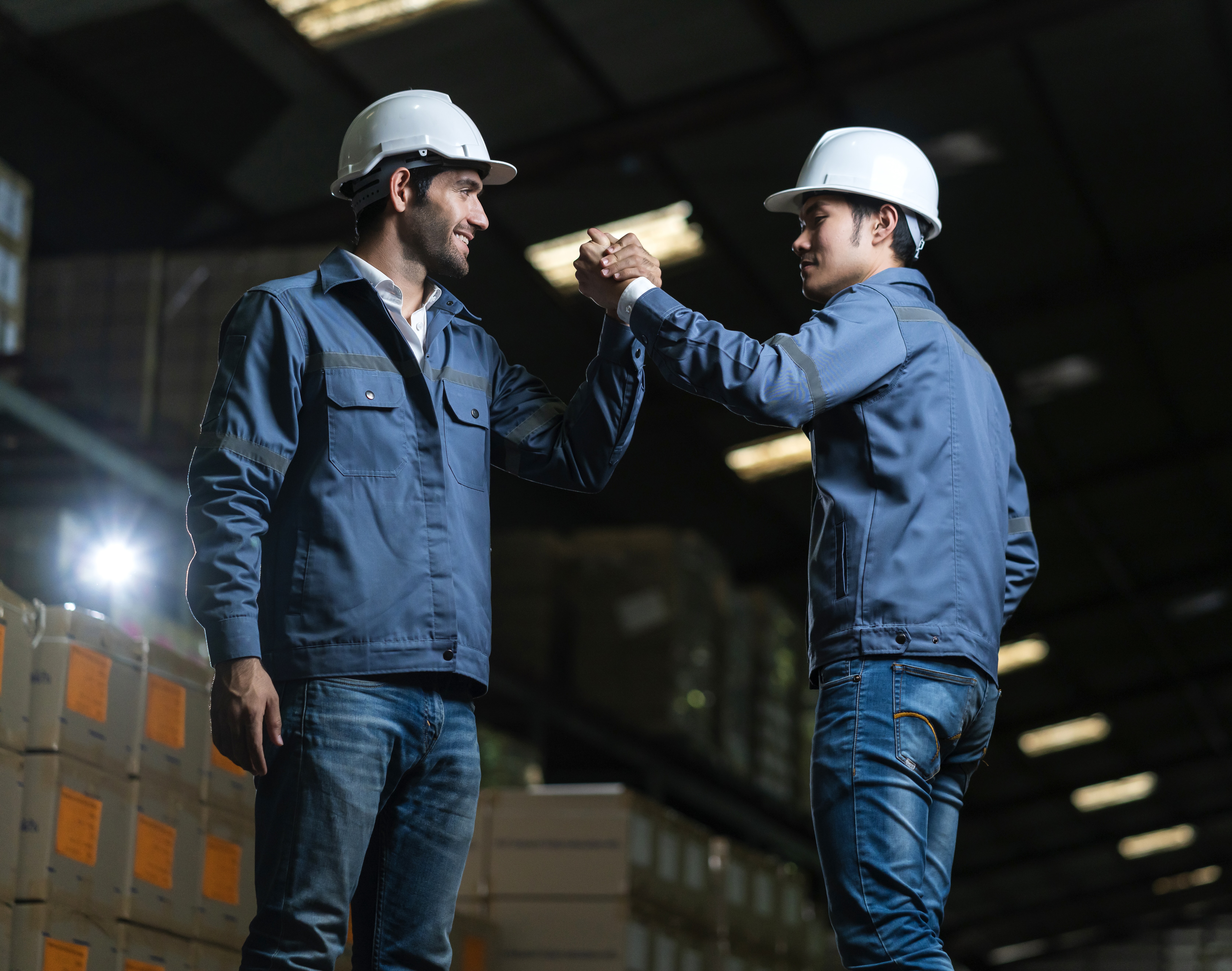 Two industrial partners greeting in a warehouse environment